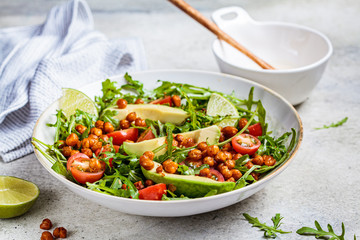 Roasted chickpea salad with avocado and tomatoes in white bowl. Healthy vegan food concept.