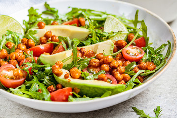 Roasted chickpea salad with avocado and tomatoes in white bowl. Healthy vegan food concept.