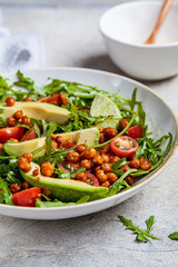 Roasted chickpea salad with avocado and tomatoes in white bowl. Healthy vegan food concept.