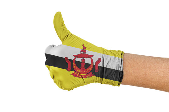 Brunei flag on a medical glove isolated on white showing thumbs up sign