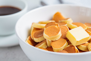 Pancake cereal with butter in a white bowl, tiny trend pancakes. Breakfast food concept.