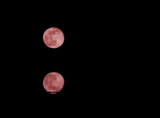 full Red moon and the reflection on the water of the sea