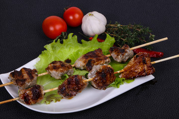 Pork kebab skewers in the plate with salad leaves and tomatoes