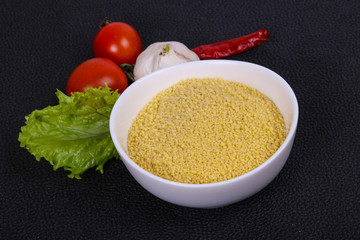 Raw couscous in the bowl served salad leaves, tomato and pepper