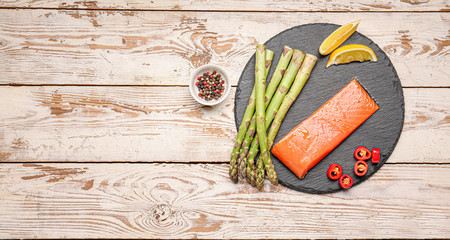 Asparagus with salmon, lemon, chili pepper and spices on table