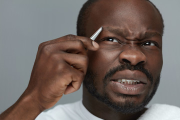 Eyebrow Shape Grooming For Male. Closeup Of Model Removing Brow Hair With Tweezers. Beauty Concept Of Facial Hair Correction.