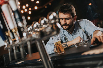 Fototapeta na wymiar Man drinking beer and smoking cigarette at pub in the night club