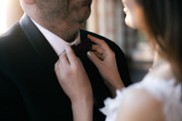 Bride straightens groom's bow tie