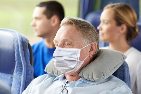 tourism, healthcare and pandemic concept - senior man wearing face protective medical mask for protection from virus disease sleeping in travel bus with neck pillow