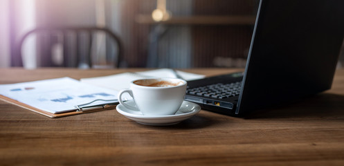 Cropped shot place of work on wooden table have coffee drink, laptop, paperwork  of investment, Concept work from home