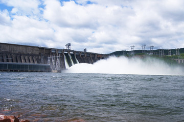 spillway on a dam which is in the mountains, streams of water with spray fly down into the river. hydroelectric power generation