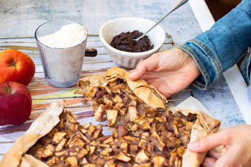 Apple crust tart pie with chocolate cream spread paste and cinnamon. Ingredients. Woman hands