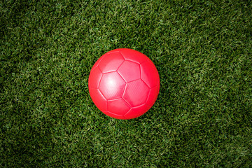 Fototapeta na wymiar a red soccer ball is lying on the lawn in the center of the field
