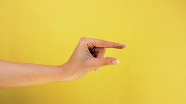 woman caucasian hand gesture of showing small size with two fingers, isolated over yellow background. Showing small thing gesture