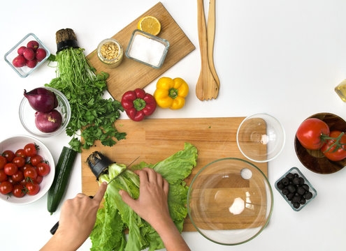 Healthy Eating, Vegetarian Food And Cooking Concept - POV Shot Of Hands Cutting Lettuce On Wooden Board At Kitchen