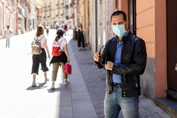 Uomo con mascherina vestito casual cammina per la città protetto dalla mascherina chirurgica