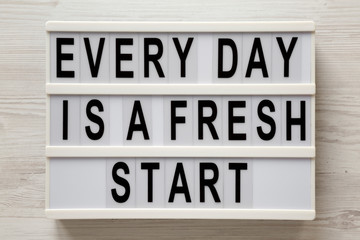 'Every day is a fresh start' words on a modern board on a white wooden background, top view. Overhead, from above, flat lay.