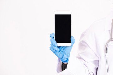 The female doctor in uniform holding mobilephone on white background.