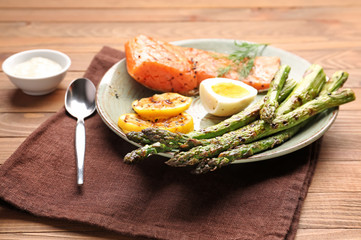Cooked asparagus with salmon, egg and lemon on table