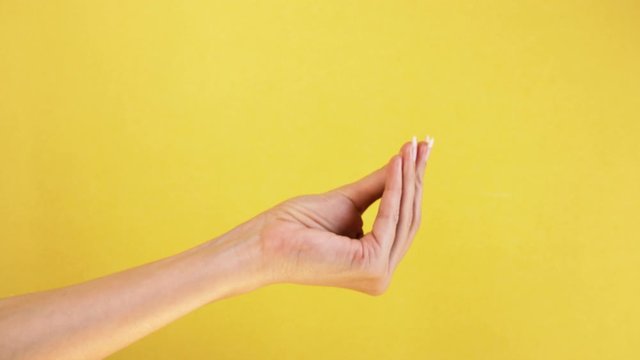 Italian gesture fingers together. isolated on yellow background female hand