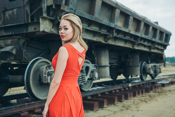 Asian girl in red dress posing on cargo carriage background