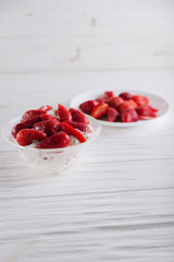 Strawberry dessert in a plate with ice cream and cream on a white wooden background