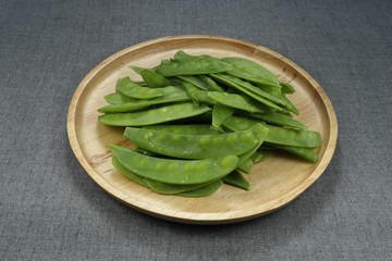 Pile of local common beans (Kidney bean) on the wooden plate. Famous raw material in Asia. Mock up of fresh vegetable in market. 
