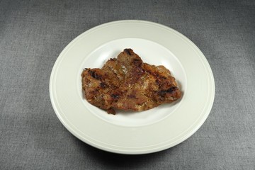 Traditional grilled pork steak on the plate. Famous roasted meat menu in Asia. High fat menu in restaurant. 