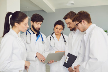 A team of doctors in a meeting discusses the diagnosis of a patient in a clinic office.