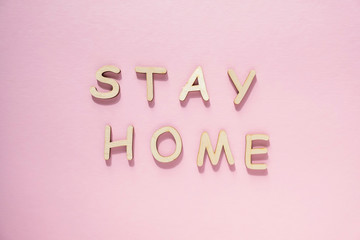Words stay home made of wooden letters on pink background. Flat lay