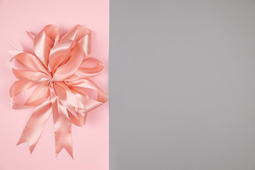 Top view of pink ribbon bow on a color background. Space for text