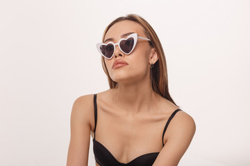 portrait of sexy asian woman with long hair, heart shaped sunglasses posing in black lingerie isolated on white background. model tests of skinny girl in bra. attractive female poses in studio