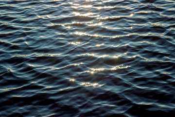 The reflection of the rays of the sun on the blue water in the Golden hour