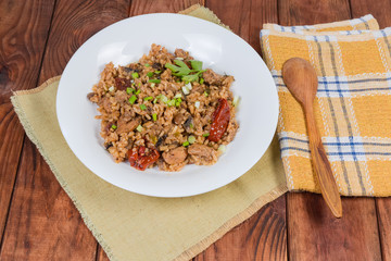 Paella with meat on dish and spoon on rustic table