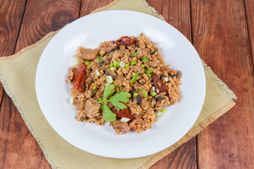 Paella with meat on dish on rustic table, top view