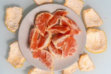 slices of grapefruit on a plate, a thick peel of fruit lies around the plate