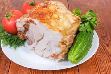 Piece of baked pork on dish with vegetables close-up