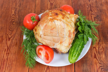 Top view of baked pork on dish among vegetables, greens