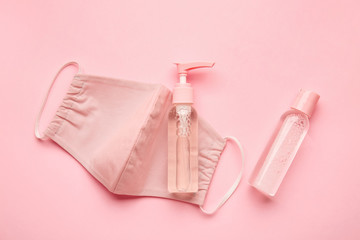 Disinfectants and medical mask on color background