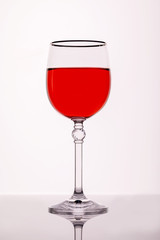 A glass of red wine on a white background with a reflection.