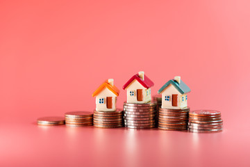 Miniature colorful house on stack coins using as property and business financial concept - Pink background