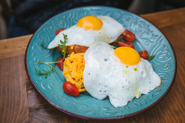 Two toasts with guacamole, cheddar and sunny side up egg. Brunch in a restaurant.