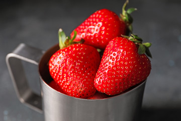 Mug with ripe strawberry on dark background, closeup