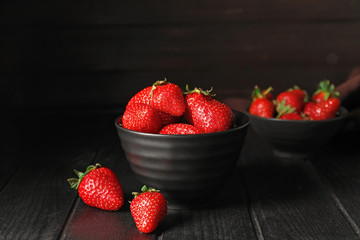 Bowl with ripe strawberry on dark background