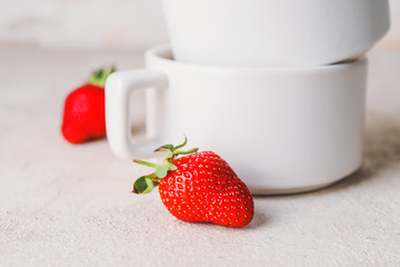 Cups with ripe strawberry on light table