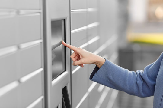 mail delivery and post service concept - close up of woman's hand choosing operation on outdoor automated parcel machine's touch screen
