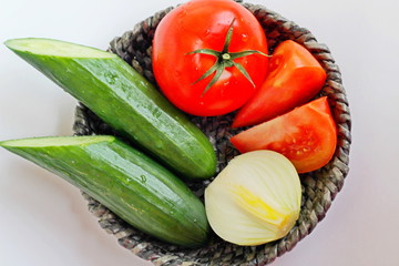 Fresh vegetables. Red tomato, cucumbers, onions in a basket.