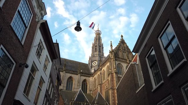 The Grote Kerk during King's Day with the Dutch flag waving on top of it during a sunny day in Haarlem