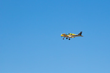 Fototapeta na wymiar yellow ultralight plane flies in the blue sky