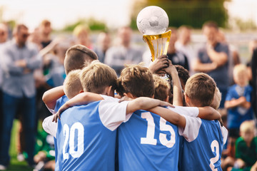 Junior Sport - Celebration. Boys in Sports Soccer Team Rising Up Golden Cup. Young Male Triumphant...